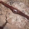Hondenhalsband met kristal en leren band op een boomstam.